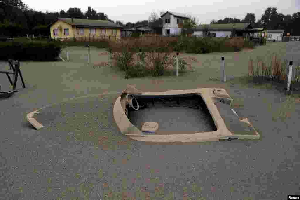 A boat is seen in a house backyard at Ensenada town which is covered with ashes from the Calbuco volcano near Puerto Varas city, April 23, 2015.