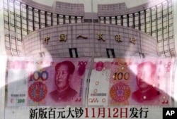 北京有人在街头报栏阅读报纸上关于中国央行宣布将发行百元新钞的消息（2015年8月11日）