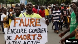 FILE - A man holds up a sign, which reads: "Faure still how many death by you," during an opposition protest calling for the immediate resignation of President Faure Gnassingbe in Lome, Togo, Sept. 6, 2017. 