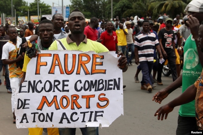 FILE - A man holds up a sign, which reads: "Faure still how many death by you," during an opposition protest calling for the immediate resignation of President Faure Gnassingbe in Lome, Togo, Sept. 6, 2017.