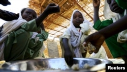 FILE - Internally displaced schoolchildren eat from the same bowl during a feeding program provided by the World Food Program at the Abushouk camp in Al Fasher in North Darfur, Sudan, Nov. 17, 2015.