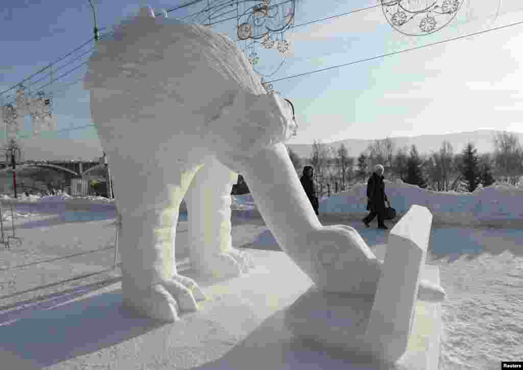 Pedestrians walk past the &quot;Computeriada&quot; snow sculpture created by the &quot;Latvia Team&quot; from Pavilosta, during &quot;The Magical Ice of the Siberia&quot; festival on the bank of the Yenisei River in Krasnoyarsk, Russia. More than 20 teams of ice and snow sculptors representing the U.S., China, Japan, Latvia and Russia are taking part in a five-day-long competition.