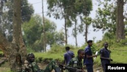 M23 rebel fighters watch the venue of a news conference by political leader Jean-Marie Runiga, in Bunagana, eastern DRC, in north Kivu province, July 21, 2012.