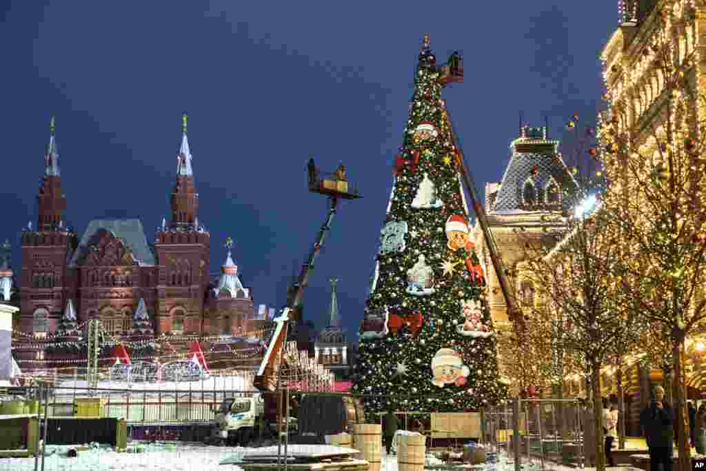 Municipal workers on cranes set up a Christmas tree in Red Square, with the Historical Museum, left, and the GUM State Department store, right, in the background, in Moscow, Russia.