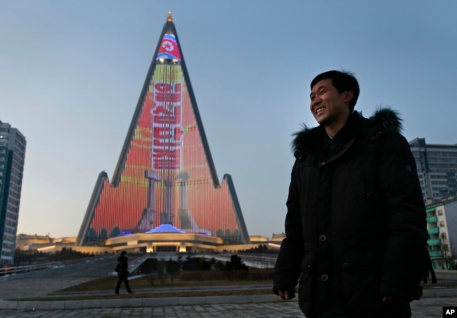 Light designer Kim Yong Il smiles, Dec. 20, 2018, as his light show on the facade of the Ryugyong Hotel is seen in the background. For several hours each night, the building that doesn't have electricity inside becomes the backdrop of a massive light show in which more than 100,000 LEDs flash images of famous statues and monuments, bursts of fireworks, party symbols and political slogans.