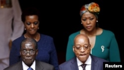 FILE: Zimbabwe's President Robert Mugabe, front left, and South Africa's President Jacob Zuma, front right, enter the Union building in Pretoria, April 8, 2015. Also pictured are Zimbabwe's first lady Grace Mugabe, rear left, and South Africa's first lady.