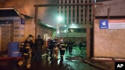 In this photo taken late Jan. 30, 2016, firefighters prepare to work to extinguish a fire at a textile workshop in Moscow, Russia. Russian officials say a fire at a textile workshop in Moscow has killed more then dozen people, including three children. 