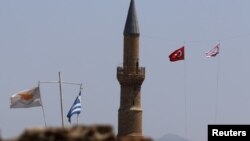 FILE - Cyprus and Greek flags along with Turkish and Turkish Cypriot flags are seen near the U.N.-controlled buffer zone in Nicosia, Cyprus, July 6, 2017.