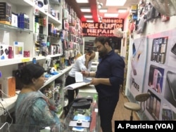 Owner of a shop selling mobiles and accessories in a posh New Delhi market, Manu Talwar (standing with register) says his sales have dropped by 30 per cent in the last year after India imposed a currency ban.