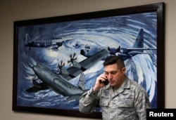 FILE - U.S. Air Force reserve citizen airman Staff Sgt. Nicholas Monteleone speaks on the phone beside a painting of planes flying through a hurricane at Keesler Air Force Base, home of the 53rd Weather Reconnaissance Squadron know as "Hurricane Hunters" in Biloxi, Mississippi, Sept. 8, 2017.