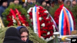 A woman comforts Boris Nemtsov's daughter Zhanna Nemtsova, second left, at the grave of Boris Nemtsov after a burial ceremony at Troekurovskoye cemetery in Moscow, Russia. March 3, 2015.