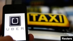 An illustration picture shows the logo of car-sharing service app Uber on a smartphone next to the picture of an official German taxi sign in Frankfurt, September 15, 2014. A Frankfurt high court will hold a hearing on a recent lawsuit brought against Ube