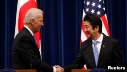 美国副总统拜登（左）和日本首相安倍晋三12月3日在东京举行联合记者会后握手。