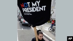 一名反对川普总统的抗议者举着“不是我的总统”的标语牌。