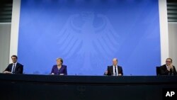 From left; Hendrick Wuest, Minister of North Rhine-Westphalia, Chancellor Angela Merkel, Finance Minister Olaf Scholz and Governing Mayor of Berlin Michael Mueller give a press conference at the Chancellery in Berlin, Germany, Dec. 2, 2021.