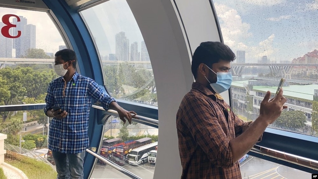 Migrant worker Natarajan Pandiarajan, right, enjoys the view on board the Singapore Flyer attraction in Singapore on March 7, 2021. (AP Photo/Annabelle Liang)