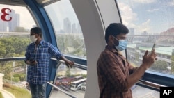 Migrant worker Natarajan Pandiarajan, right, enjoys the view on board the Singapore Flyer attraction in Singapore on March 7, 2021. (AP Photo/Annabelle Liang)
