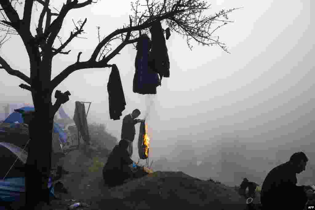 A man burns a pair of trousers to make it a bonfire during a foggy morning at a makeshift camp at the Greek-Macedonian border near the Greek village of Idomeni where thousands of refugees and migrants are stranded.