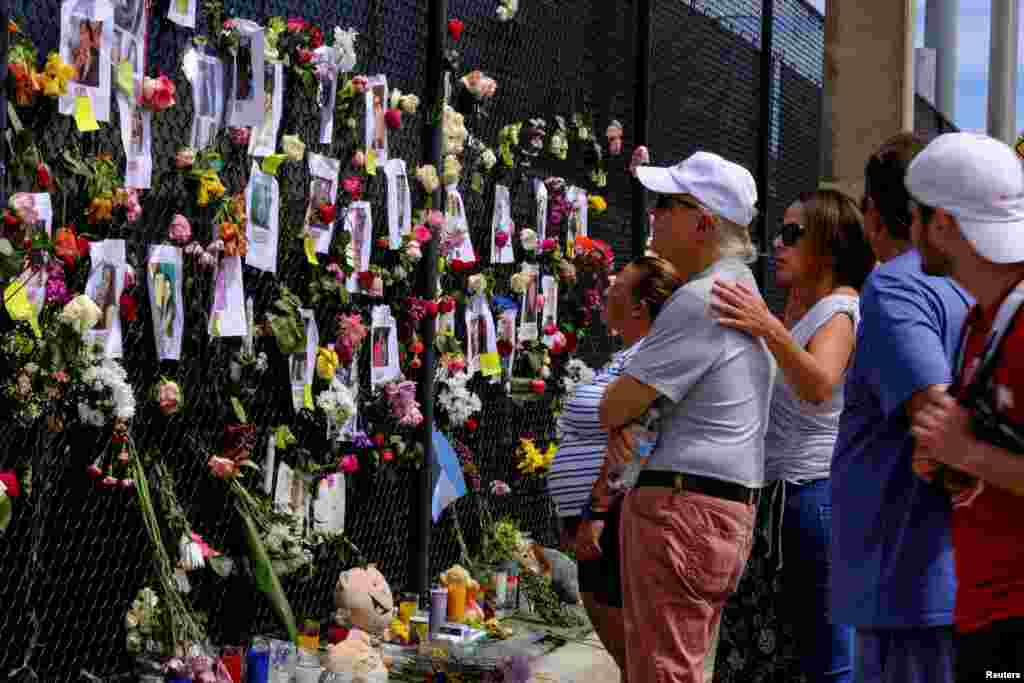 La gente llora en el sitio conmemorativo creado por los vecinos frente al edificio parcialmente derrumbado donde el personal de rescate contin&#250;a la b&#250;squeda de v&#237;ctimas.