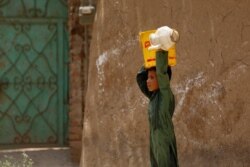 A boy from an Afghan refugee family, carries a bucket of water on his head, filled at a nearby tap, on the outskirts of Peshawar, Pakistan, June 20, 2019.