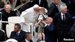 Pope Francis kisses a child at the end of a mass in Saint Peter's Square at the Vatican, May 19, 2013. 