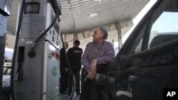 هاوڵاتیـیه‌کی ئێرانی له‌ به‌نزینخانه‌یه‌کی تاران به‌نزین ده‌کاته‌ ئۆتۆمبیله‌که‌ی، یه‌کشه‌ممه‌ 19 ی دوازده‌ی 2010