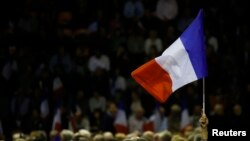 FILE - A supporter raises a French flag at a campaign rally in Nimes, France, Nov. 18, 2016.