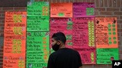 Un hombre frente a carteles que muestran los precios de los productos en dólares estadounidenses frente a una tienda de abarrotes en Quinta Crespo Caracas, el 19 de enero de 2021.