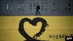 FILE - A man walks down steps past a tribute to victims of the Sewol ferry, in Seoul, South Korea.