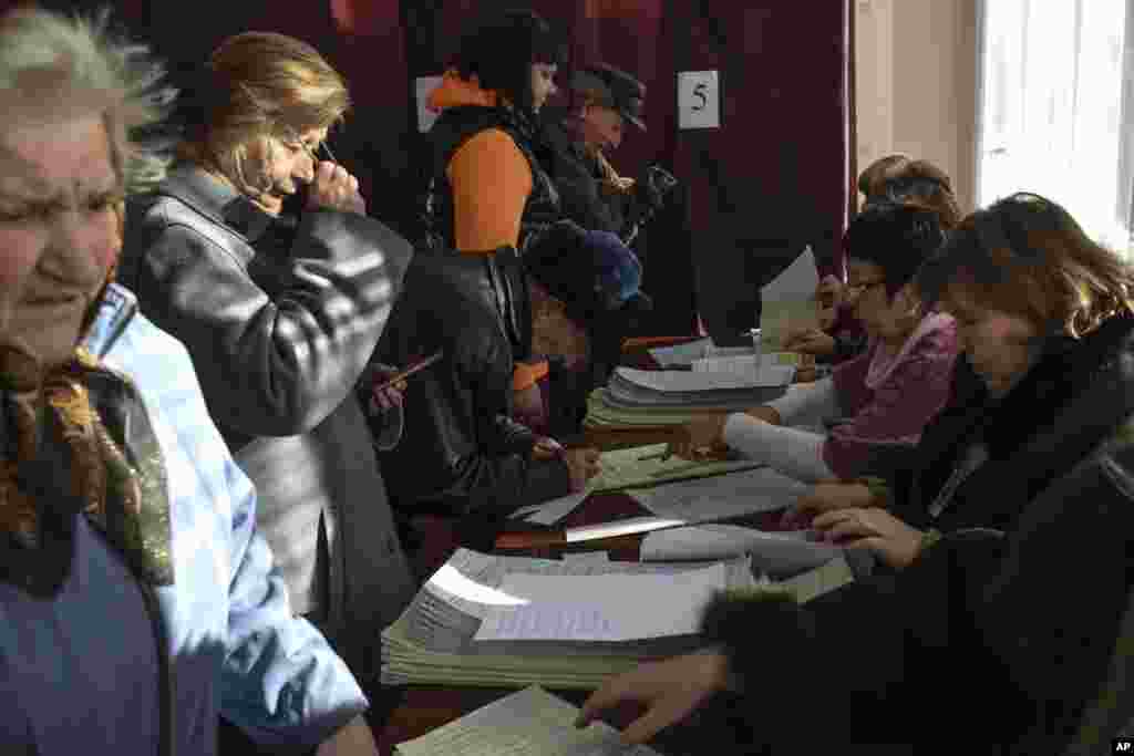 People register their names before casting their vote for the parliamentary elections at a polling station in Konstantinovka, Donetsk region, eastern Ukraine, Oct. 26, 2014. 