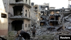 A man stands next to destroyed and damaged buildings in Sabri, a central Benghazi district, Libya, Aug. 15, 2017.