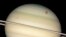FILE - This image provided by NASA captures the transit of several moons across the face of Saturn. The giant orange moon Titan – larger than the planet Mercury – can be seen at upper right.