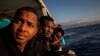 FILE - Nigerian men who were rescued off the Libyan coast on Friday, watch the sea from the deck of the Open Arms rescue vessel as the ship approaches the port of Messina, Italy, Jan. 15, 2020. 