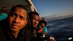 FILE - Nigerian men who were rescued off the Libyan coast on Friday, watch the sea from the deck of the Open Arms rescue vessel as the ship approaches the port of Messina, Italy, Jan. 15, 2020. 