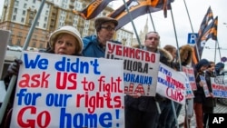 FILE - Protesters holding anti-American signs are seen gathered in front of the U.S. Embassy at a rally against what they see as American mingling in Russia's internal affairs, in Moscow, Russia, March 7, 2015.