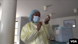A health official at Wilkins Hospital in Harare, Zimbabwe, prepares to inoculate with Sinopharm vaccine, March 11, 2021. (Columbus Mavhunga/VOA)