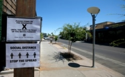 Social distancing signs are posted at one of the bars closed for the next 30 days due to the surge in coronavirus cases, June 30, 2020, in Scottsdale, Ariz.