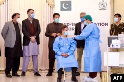 Pakistan's Prime Minister Imran Khan, center back, watches as the first Chinese-made COVID-19 vaccine is administered to a front-line health worker in Islamabad, Feb. 2, 2021, in this photograph taken by Pakistan's Press Information Department.