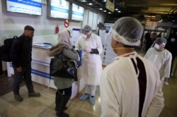 Afghan health workers wearing protective gear speak with passengers who arrived from China during a screening process for coronavirus, at the Hamid Karzai International Airport in Kabul, Afghanistan, Feb. 3, 2020.