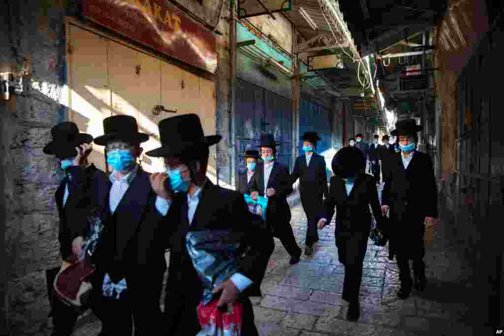 گروهی از یهودیان ارتدوکس با ماسک در بخش قدیمی شهر اورشلیم. دولت اسرائیل از مردم خواسته است که در اماکن عمومی ماسک بزنند. 