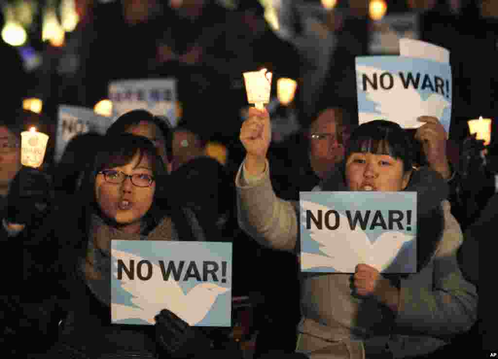 People hold signs at a candlelight vigil calling for peace on the Korean peninsula, in Seoul November 29. South Korean President Lee Myung-bak vowed retaliation against any further provocation by the North after it attacked an island last week. (Kim Kyun