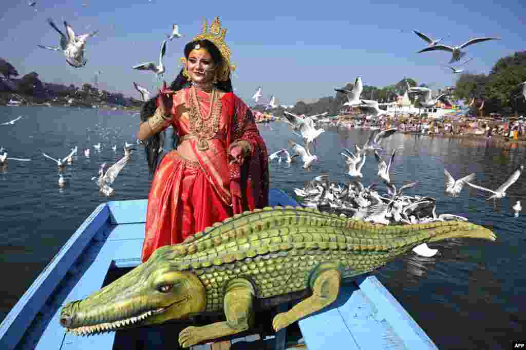 An artist dressed as Goddess Narmada, the river deity named after the Narmada River, accompanied by her vahana (deity&#39;s carrier), the crocodile, poses for pictures ahead of Narmada Jayanti celebrations in Jabalpur.