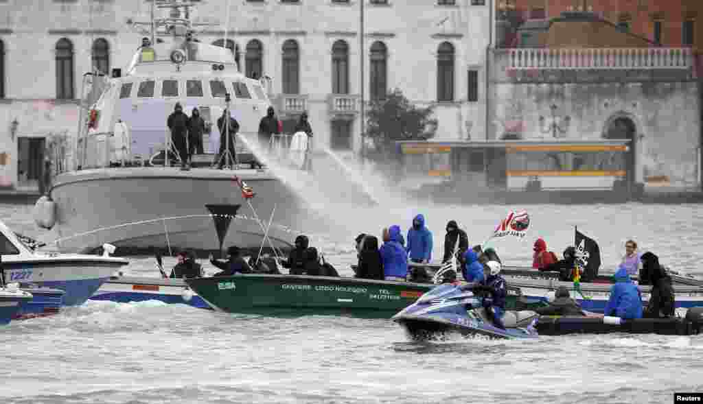 Guardia di Finanza police spray water cannons at NO TAV (no high speed train) protesters in the Venice lagoon, before the meeting between Italian Prime Minister Matteo Renzi and French President Francois Hollande during the annual Franco-Italian summit in Venice, Italy.