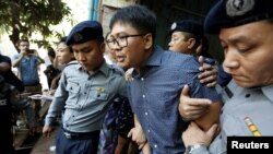 Wartawan Reuters Wa Lone (tengah) dikawal oleh polisi setelah sidang di pengadilan Yangon, Myanmar, Rabu, 11 April 2018. 