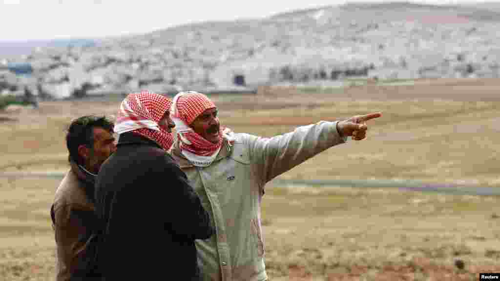 Turkish Kurds watch the Syrian town of Kobani from near the Mursitpinar border crossing, on the Turkish-Syrian border in the southeastern town of Suruc, Oct. 19, 2014. 