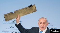 PM Israel Benjamin Netanyahu memegang apa yang disebutnya sebagai potongan drone Iran yang ditembak jatuh di wilayah udara Israel, ketika berpidato di Konferensi Keamanan Munich, Jerman, 18 Februari 2018. 