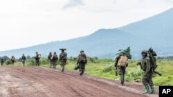 FILE - M23 rebels walk on a road as they leave after a ceremony to mark the withdrawal from their positions in the town of Kibumba, in the eastern of Democratic Republic of Congo, Friday, Dec. 23, 2022.