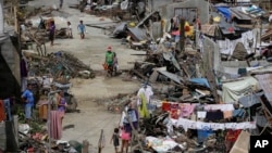 Survivors of Typhoon Haiyan walk amid ruins of their homes in Maraboth, Philippines, Nov. 14, 2013.