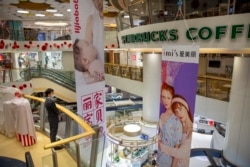 FILE - A security officer wearing a face mask stands in a shopping mall with a number of stores that remained closed in Beijing, Feb. 3, 2020.