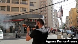 A Shiite fighter takes aim during clashes in the area of Tayouneh, in the southern suburb of the capital Beirut, on Oct. 14, 2021.